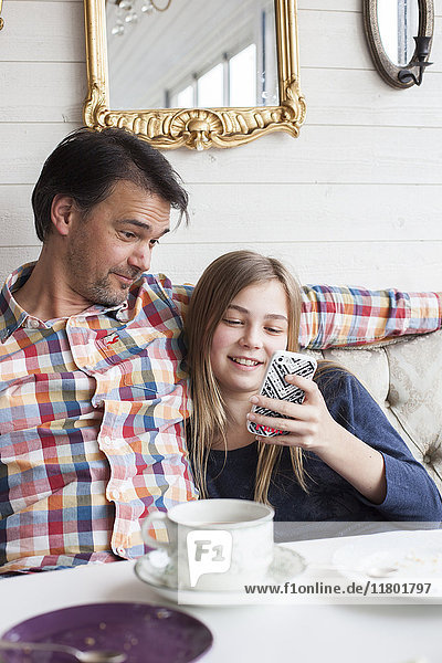 Mädchen mit Vater schaut auf das Telefon