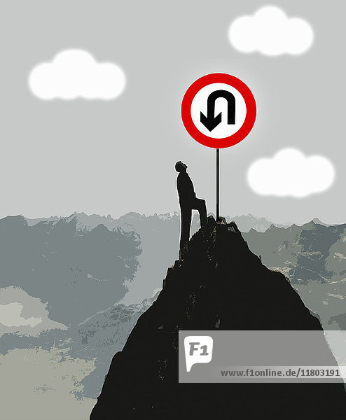 Mann steht auf einem Berg und schaut auf großes Kehrtwende-Schild