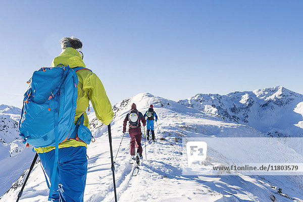 Rückansicht von Skifahrern  die auf einem Bergkamm gegen den Himmel laufen