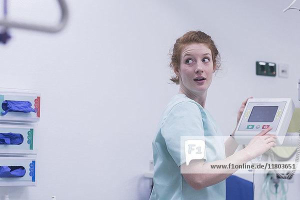 Weibliche Krankenschwester schaut bei der Bedienung medizinischer Geräte über die Schulter