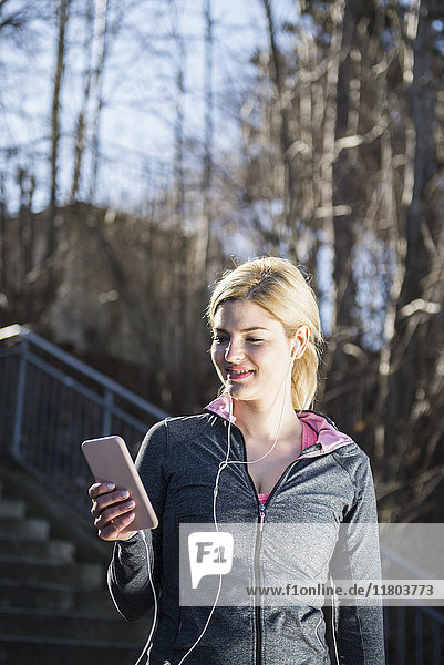 Frau in Sportkleidung hört Musik auf einem Smartphone