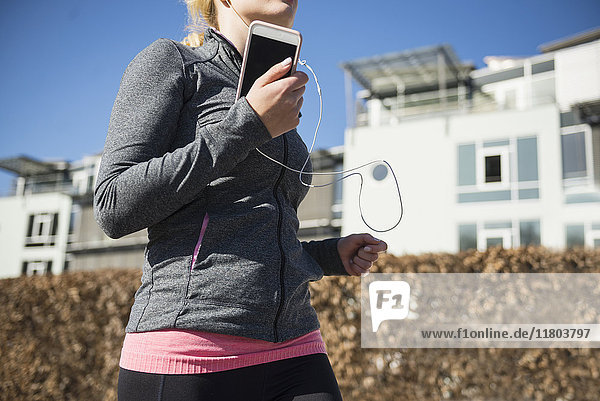 Frau joggt und hört Musik auf dem Smartphone