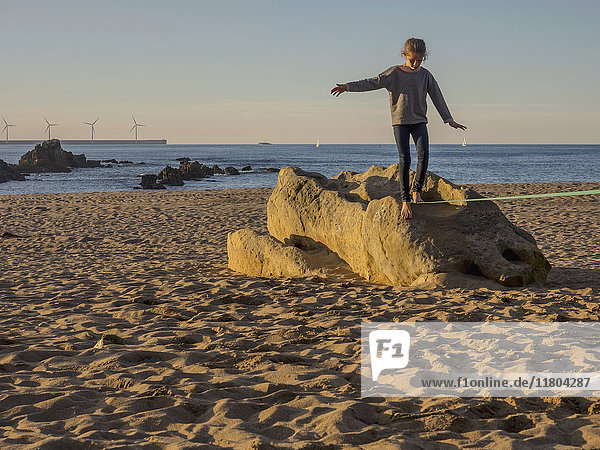 Mädchen balanciert auf einer Slackline an einem Strand in Nordspanien