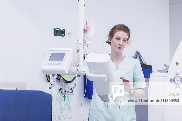Female nurse holding glucose bottle and operating medical machine