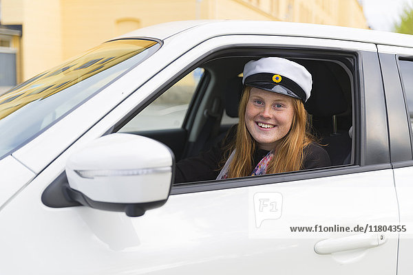 Girl wearing graduation cap in car
