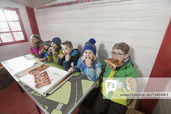 Children eating pepperoni pizza at restaurant