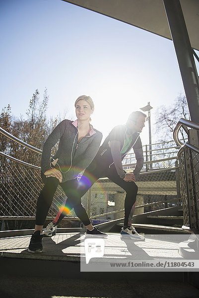 Man and woman in sportswear stretching outdoors
