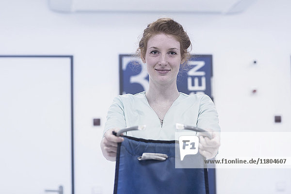 Portrait of young nurse holding body protector against x-ray