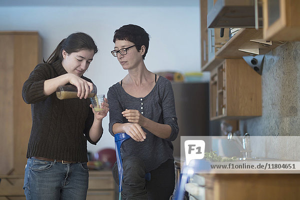 Daughter pouring juice in glass for her mother with broken leg