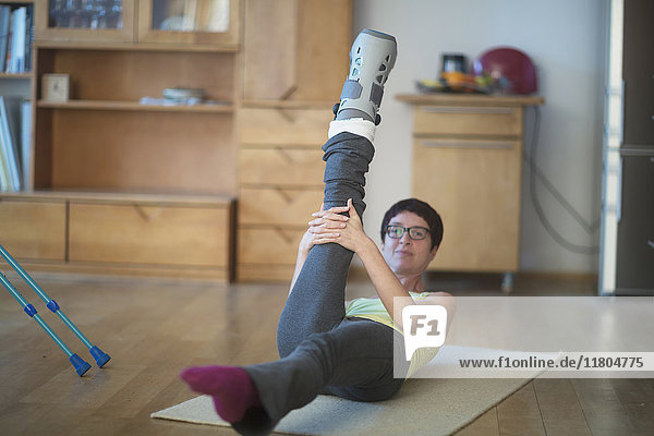 Woman doing stretch exercise with a broken leg