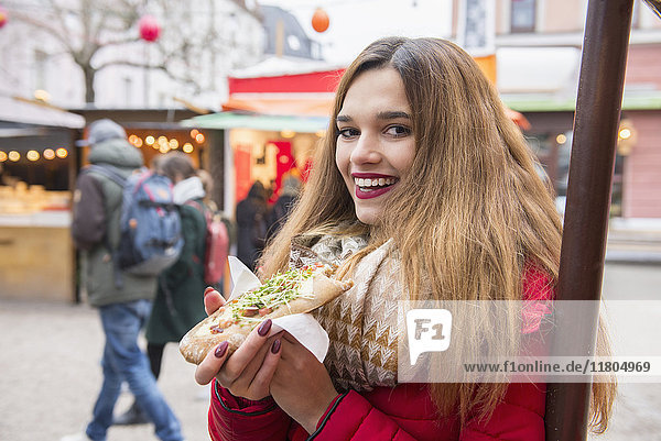 Portrait of young woman eating street food
