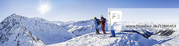 Drei Skifahrer stehen auf einem schneebedeckten Berg