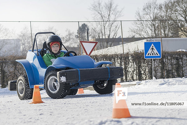 Boy driving electric toy car on snow covered road