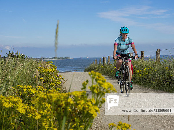 Woman riding bike on dirt track near sea