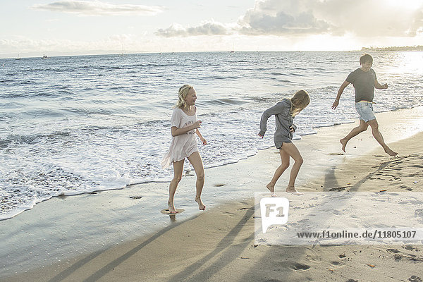 Vater mit Töchtern läuft am Strand
