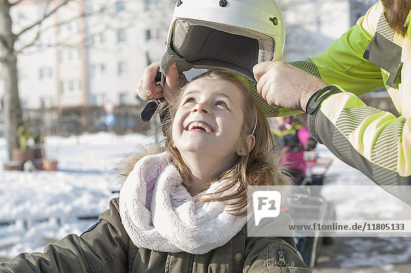 Man helping girl in wearing helmet