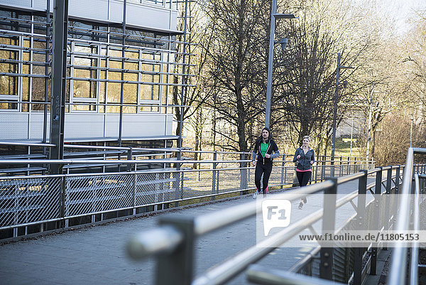 Man and woman jogging on bridge in city