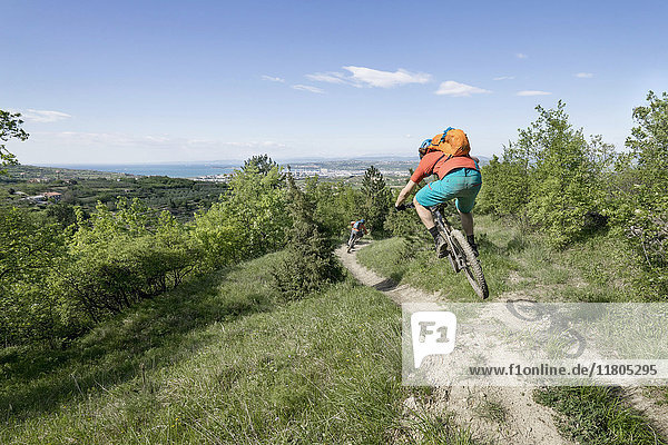 Young biker jumping in mid-air while riding through narrow trail