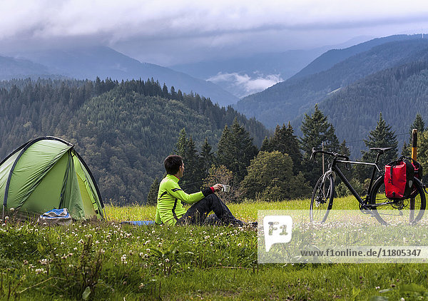 Mann auf seinem Campingplatz mit Blick auf die Berge