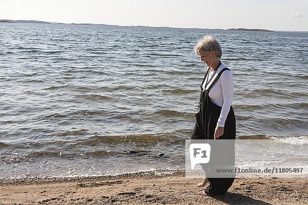 Reife Frau am Strand mit Blick aufs Meer