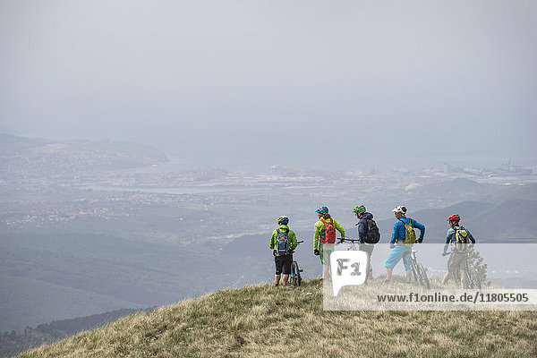 Mountain bikers looking at view while standing on top of mountain