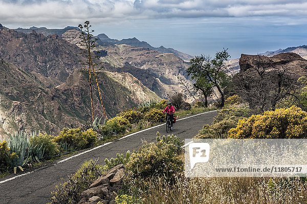 Woman riding electric bicycle on mountain road