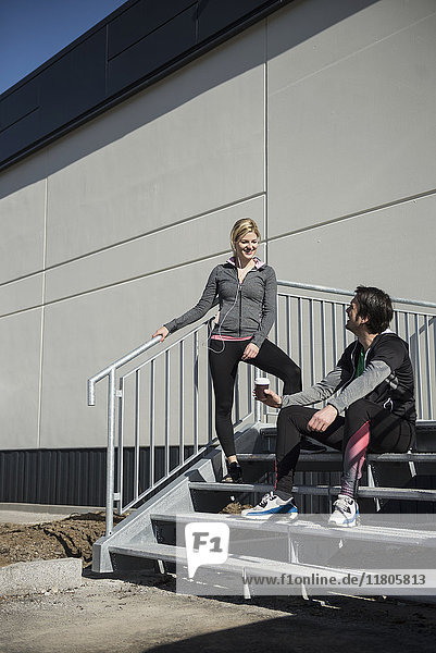 Mann und Frau in Sportkleidung entspannen sich nach dem Training auf einer Treppe