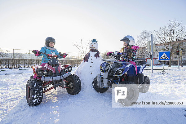 Girls riding quad bike on snow field