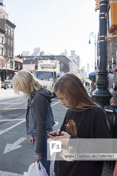 Teenager-Mädchen benutzt Mobiltelefon auf der Straße