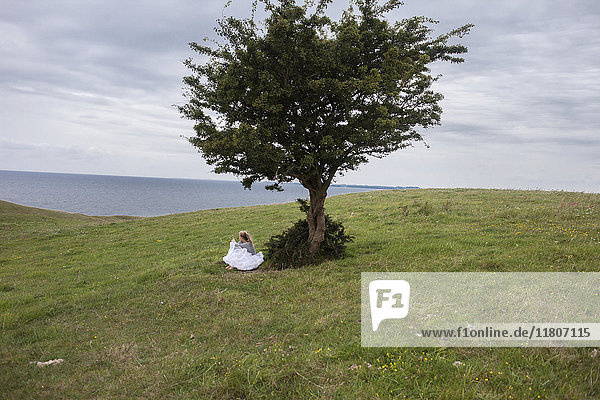 Frau sitzt unter einem Baum