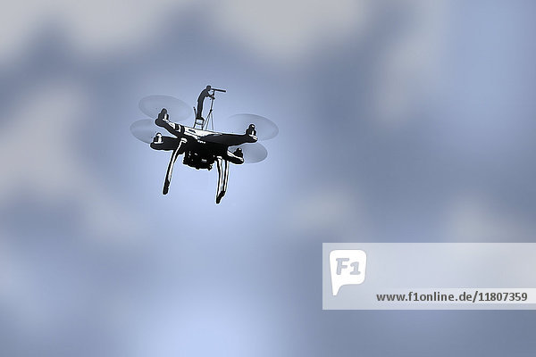 Mann auf einer fliegenden Drohne schaut durch ein Fernrohr