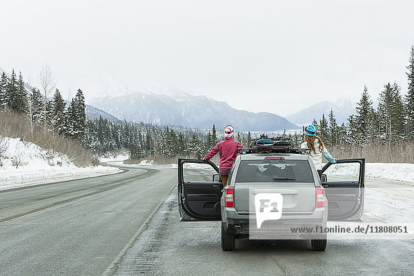Kaukasische Frauen stehen im Auto im Winter bewundern landschaftliche Aussicht