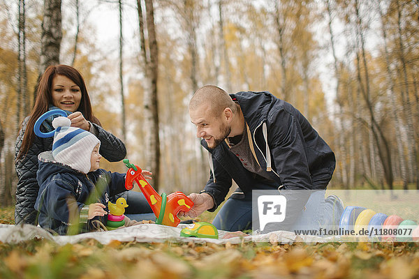 Paar aus dem Nahen Osten spielt im Herbst mit seinem kleinen Sohn im Park