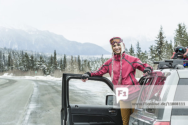 Lächelnde kaukasische Frau im Auto stehend im Winter