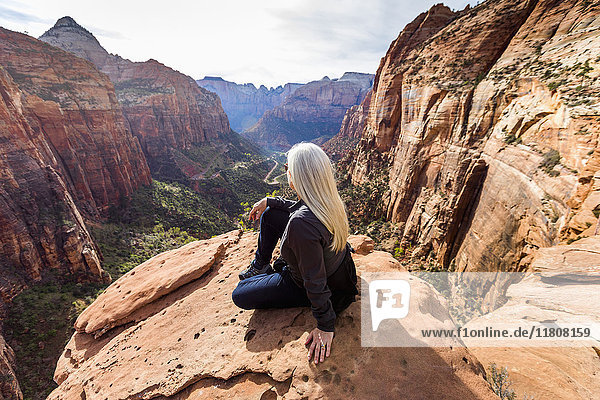 Caucasian woman sitting on rock admiring scenic view of rock formations