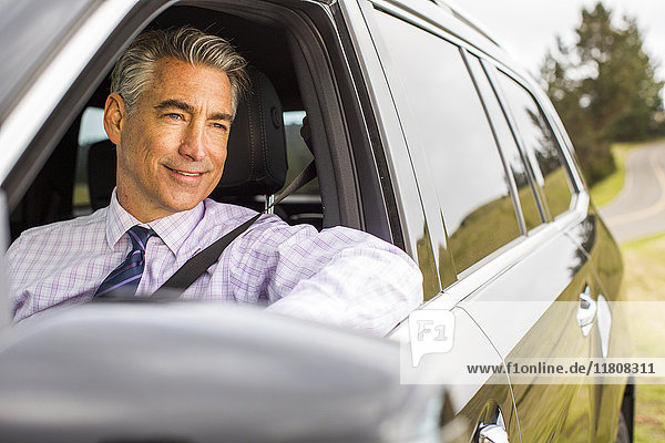 Smiling Caucasian businessman driving car