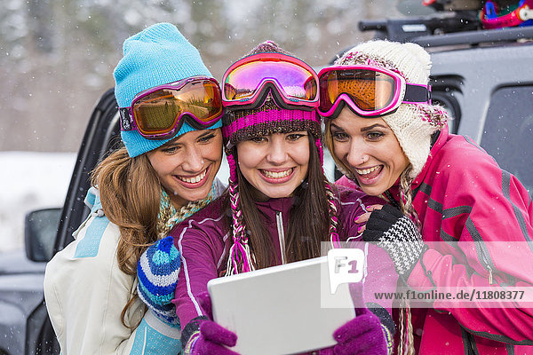 Women posing for selfie with digital tablet in winter