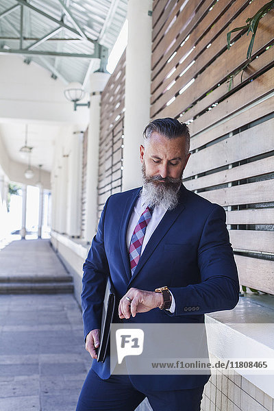 Caucasian businessman on sidewalk checking the time on wristwatch