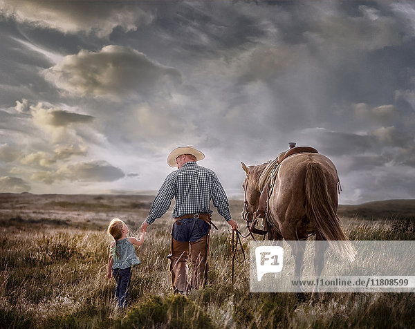 Kaukasischer Vater und Tochter gehen mit ihrem Pferd auf einem Feld spazieren
