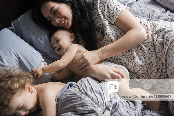 Kaukasische Mutter spielt mit Söhnen im Bett