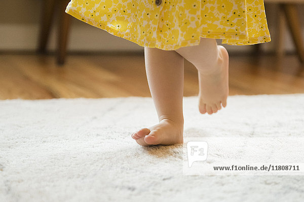 Barfuß kaukasischen Baby Mädchen zu Fuß auf Teppich
