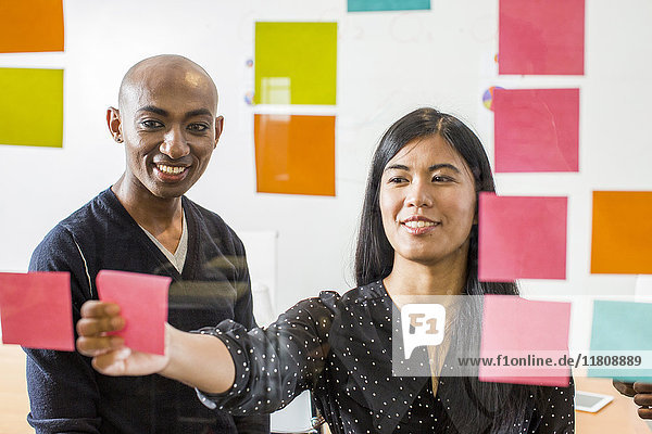 Woman and man reading adhesive notes in office