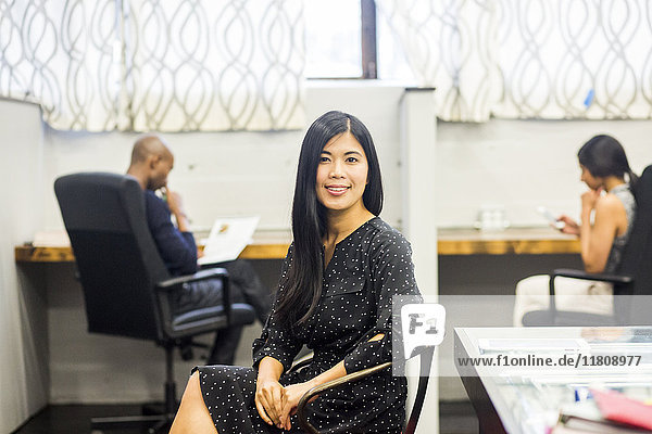 Porträt einer lächelnden asiatischen Frau  die im Büro sitzt