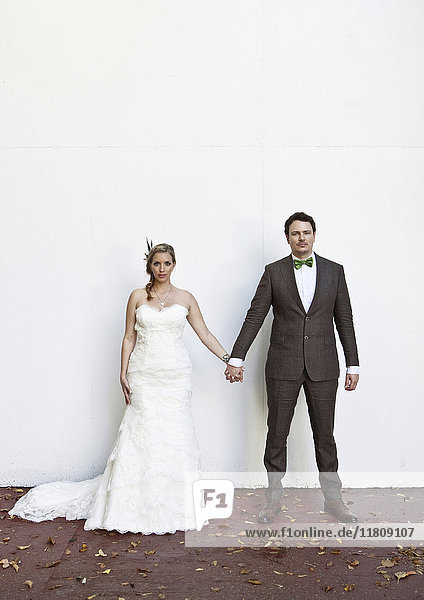 Ernste kaukasische Braut und Bräutigam halten Hände