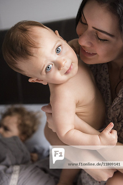 Caucasian mother holding baby son in bed