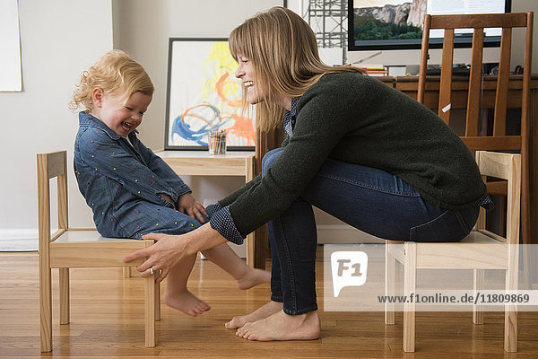 Caucasian mother and daughter sitting on small chairs in home office