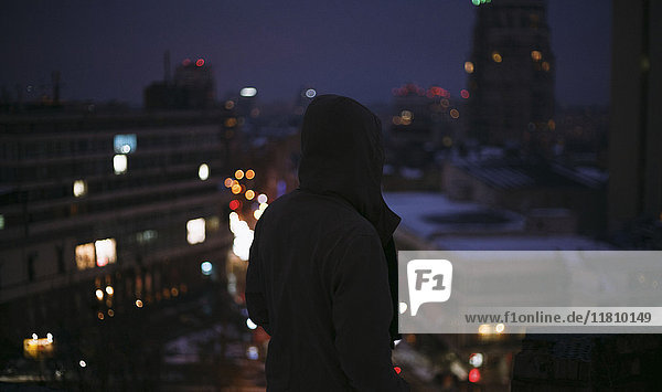 Silhouette eines Mannes auf einem Dach in der Stadt bei Nacht
