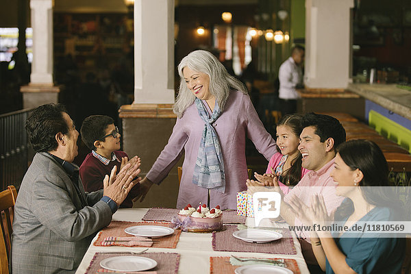 Family celebrating birthday of older woman in restaurant