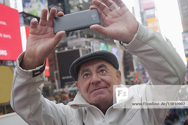 Hispanischer Mann posiert für Handy-Selfie in der Stadt