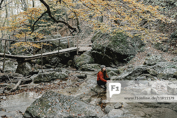 Kaukasische Frau sitzt auf einem Felsen im Bach